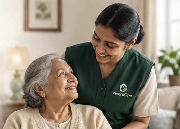 A smiling ViveraOne caregiver in a green uniform with an elderly woman at home